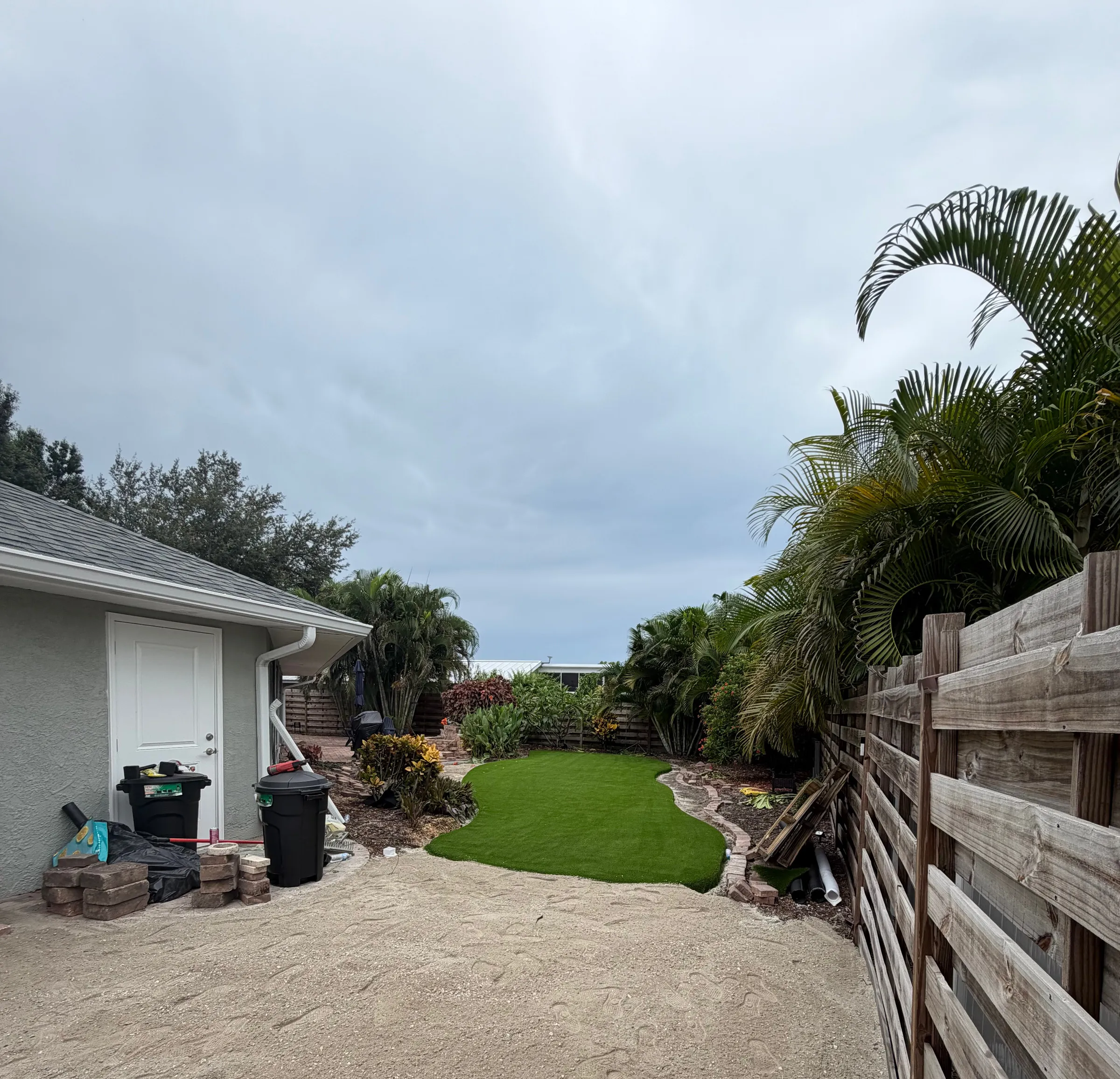 Graded base exposed in a side yard beside a finished section of turf, mid-install