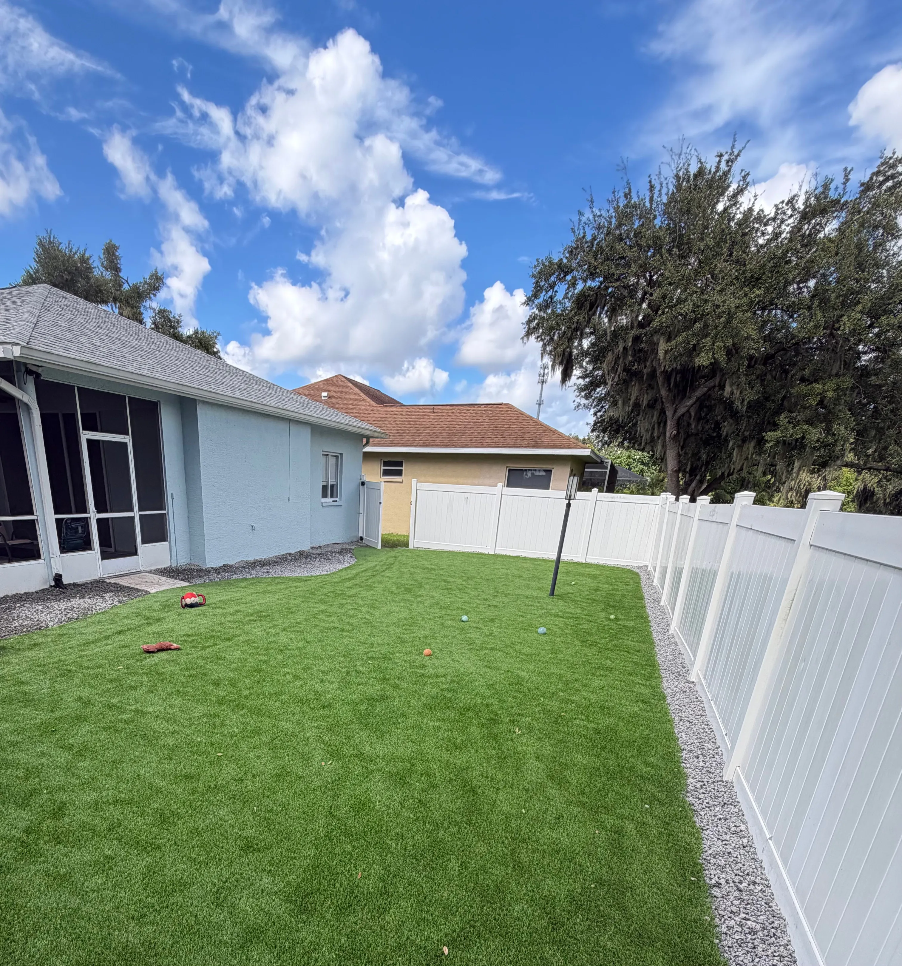Artificial turf backyard with a white vinyl privacy fence
