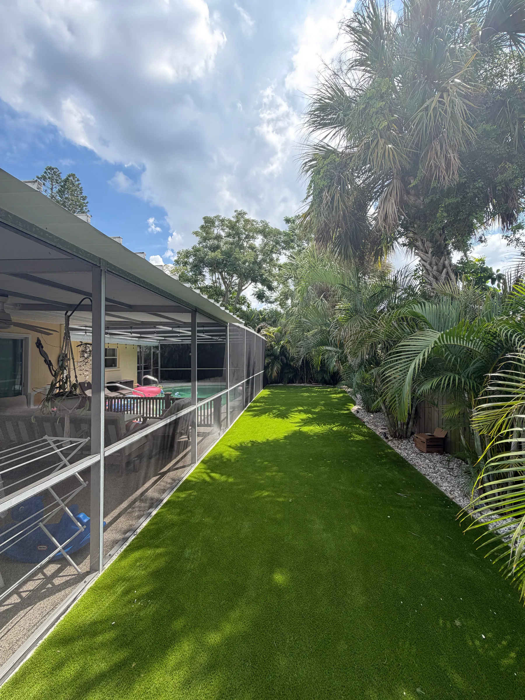 Artificial turf running along the outside of a screened pool enclosure