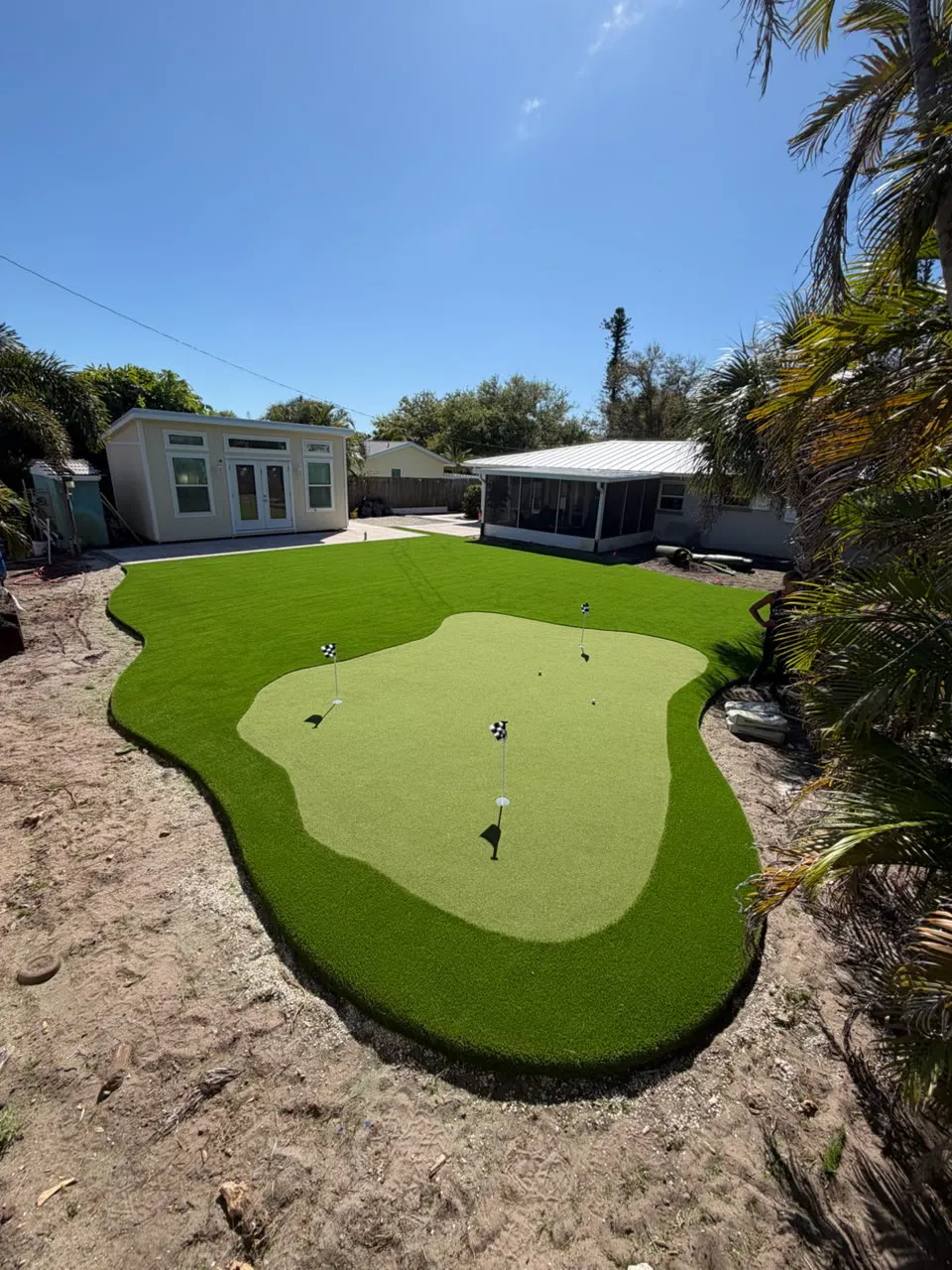 Kidney-shaped putting green with three cups and a darker fringe collar