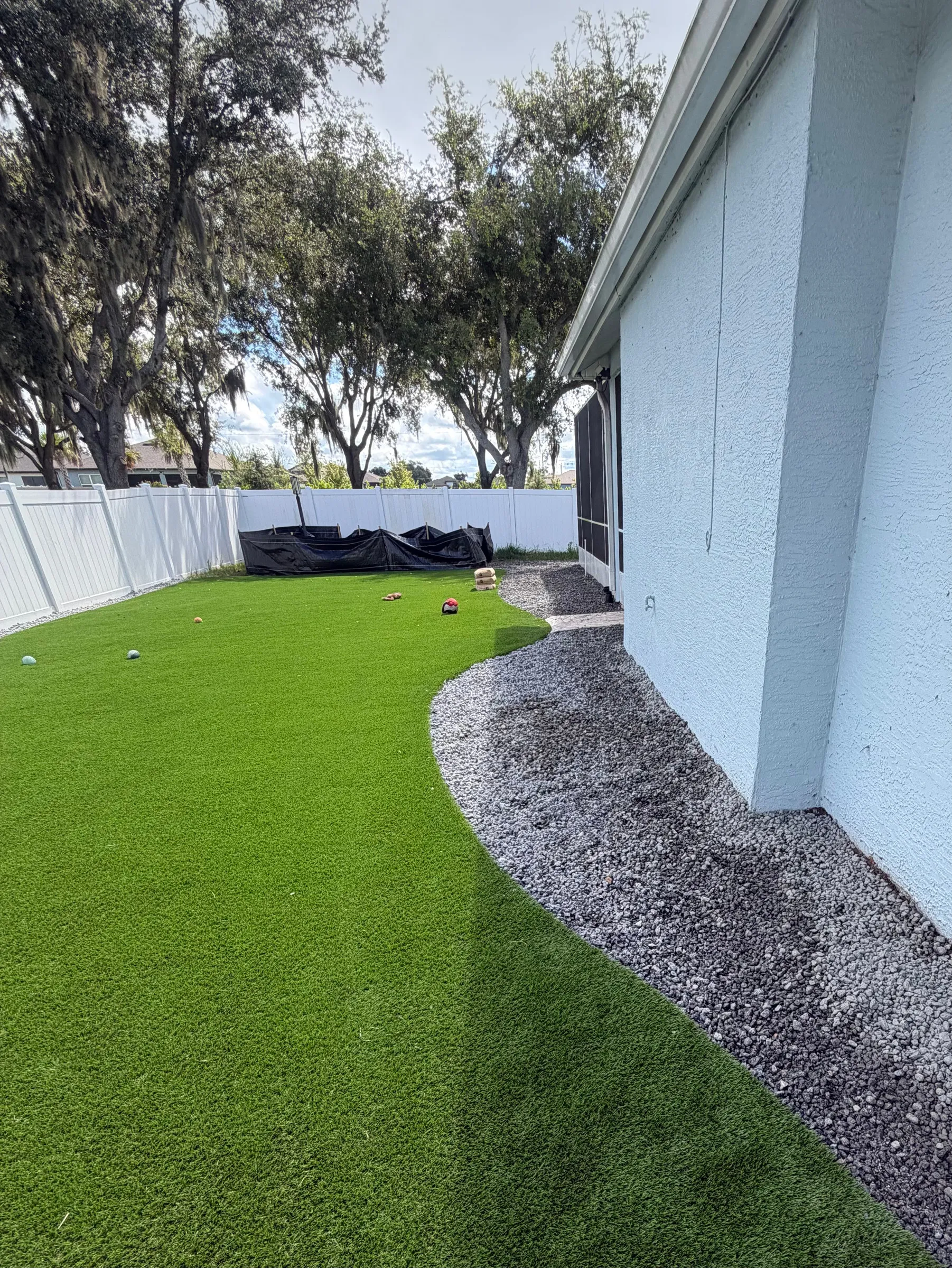 Artificial turf side yard with a gravel drainage edge along the house